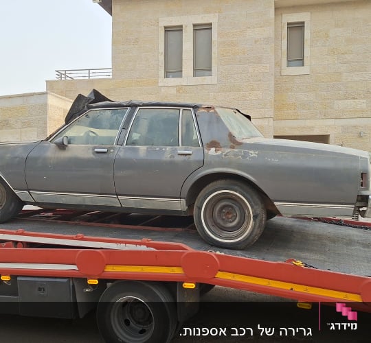 רכב ישן על גרר מול בית אבן